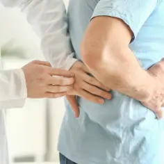 Lekarz bada pacjenta z bólem brzucha, który może być objawem zespołu Alporta.