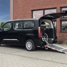 Czarny van z rampą dla wózka inwalidzkiego. Dostępne są środki ułatwiające mobilność, takie jak bezzwrotna pożyczka dla niepełnosprawnych, by ułatwić podróżowanie.