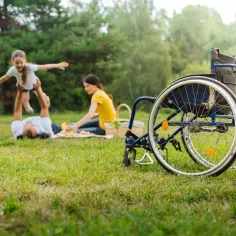 Rodzina na pikniku. Wózek inwalidzki obok, symbol ulgi na dziecko niepełnosprawne.