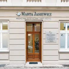 Elegancka fasada kliniki medycyny estetycznej "Marta Jasiewicz" z drewnianymi drzwiami i oknami.