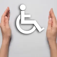 Dłonie otaczają białe symbole niepełnosprawności, symbolizując wsparcie i akceptację.