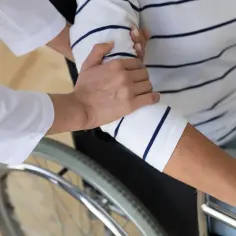 Opiekunka wspiera pacjentkę na wózku inwalidzkim. Czy świadczenie pielęgnacyjne wlicza się do lat pracy?