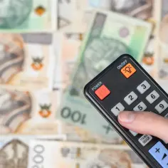 Dłoń z pilotem naciska przycisk "1" na tle polskich banknotów. Czyżby to symbol zwolnienia z abonamentu RTV?