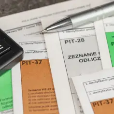 Kalkulator i długopis na dokumentach PIT-37, PIT-28 i PIT-36.