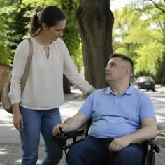Kobieta wspiera mężczyznę na wózku inwalidzkim. To przyszłość, gdzie asystent osoby niepełnosprawnej 2026 zapewnia wsparcie i niezależność.