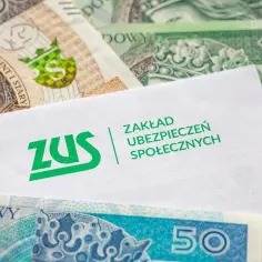 Biała koperta z logo ZUS leży na polskich banknotach. Może to być wniosek o dodatek pielęgnacyjny.