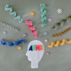 Kolorowe spirale i kwiatki otaczają głowę z literami ADHD. Obraz symbolizuje chaos myśli i wyzwania związane z ADHD u kobiet.