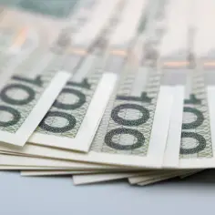 Stos banknotów 100 zł, symbolizujący pfron dofinansowanie do samochodu.