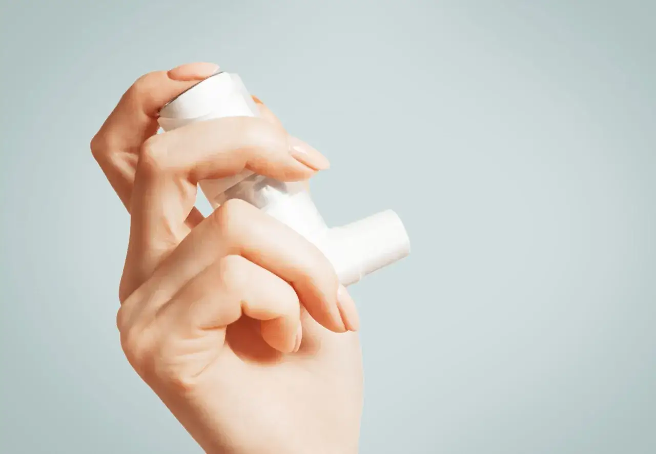 Dłoń trzymająca inhalator, pomoc w łagodzeniu objawów astmy alergicznej.